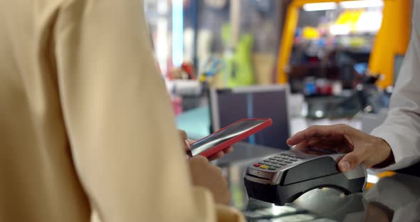Young woman use smartphone paying over contactless transaction machine