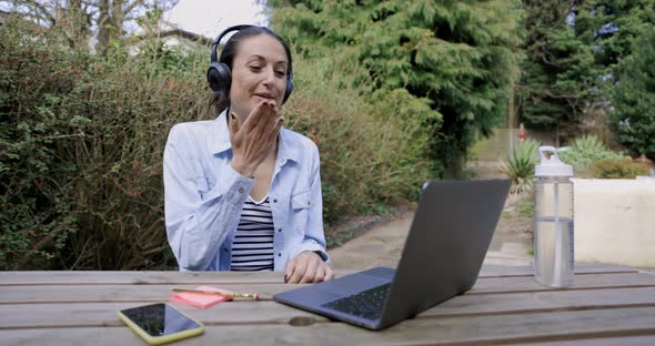 Woman with headphones ending video call with blow kiss