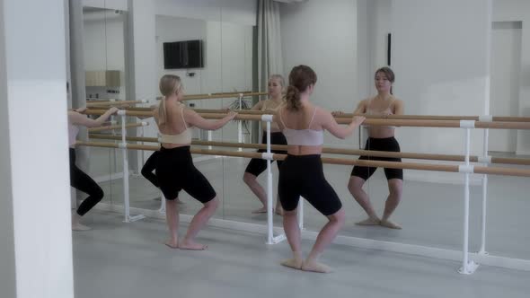 Ballerinas warm up in the studio in front of a mirror in a white bright dance hall, warm-up alt