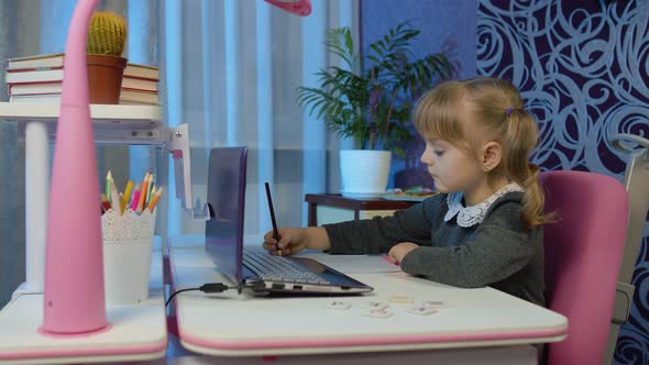 Child Schoolgirl Learning Lessons Distance Education at Home Sitting at Table Using Laptop Computer alt