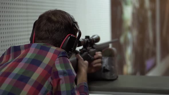 Close Up of a Man Shooting Use Rifle at Shooting Range in Headphones alt