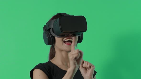 VR game playing. Asian teenager woman playing virtual reality game by VR headset. Blue or green BG