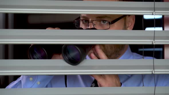 A businessman in Glasses and with Binoculars in Hands Wants to spy on the Neighbor. alt