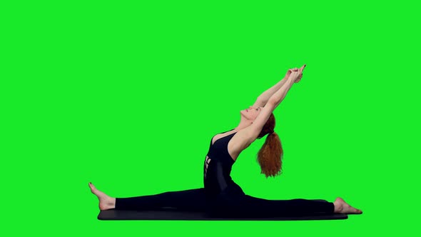 Sporty Woman Doing Splits During Yoga Practice Against Green Screen