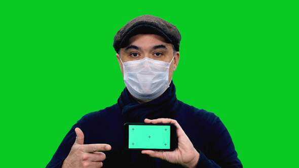 Adult Man in Protective Mask and Hat Telling and Holding Smartphone with Green Screen