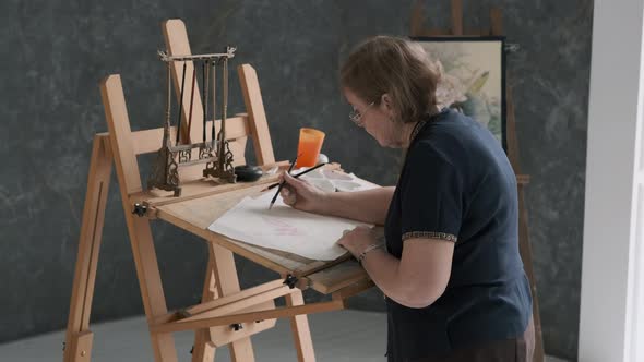 Senior Artist Painting at Easel in Art Studio alt