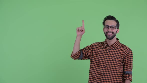 Happy Young Bearded Persian Hipster Man Talking and Pointing Up alt