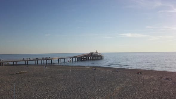 Drone Taking Off over a Pier during Golden Hour revealing a vast blue Sea alt