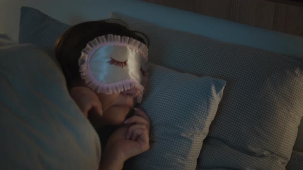 Middleaged Brunette Woman Puts on a Mask on Her Face and Sleeps at Home Cinematic Shot