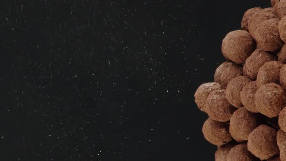 Vertical Video Closeup Gold Luster Dust Pours to Pile of Chocolate Truffles on Black Background