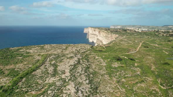 AERIAL: Steep Slopes of Ta Cenc Cliffs near Blue Mediterranean Sea on Windy Day