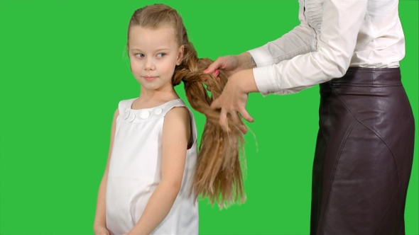 Mother Makes Daughter Hairstyle on A Green Screen, Chroma Key