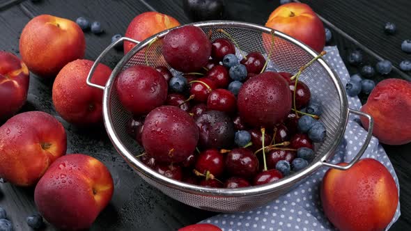 Nectarine and a Handful of Sweet Cherries Lie on a Black Wood Background alt