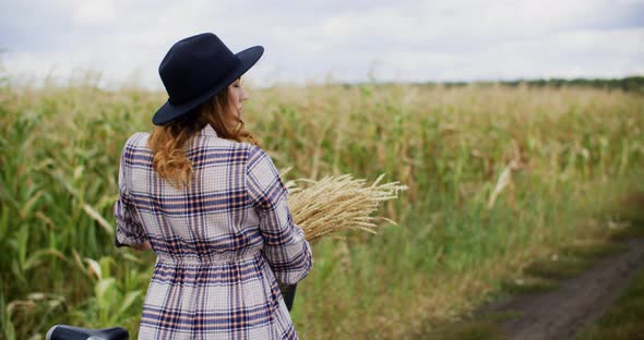 Back View of Young Woman with Bicycle on Rural Path