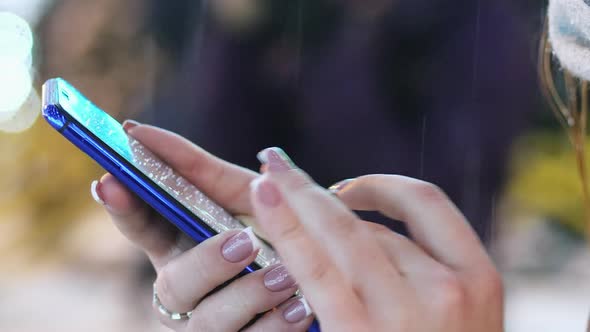 Closeup of a Woman's Hand Uses the Mobile Phone App in the Snowy Evening, Christmas and New Year alt