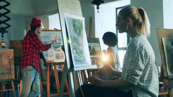 Art Students are Painting While Their Teacher is Talking to Them alt