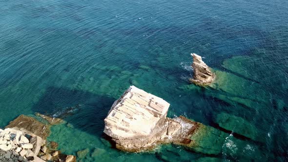 Aerial Footage of Three Pillars on a Rocky Coast with Clear Blue Water