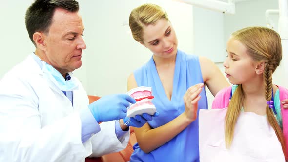 Dentist showing young patient how to brush teeth alt