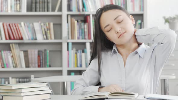 Young Attractive Female Student Stretching Her Back While Studying at the Library alt