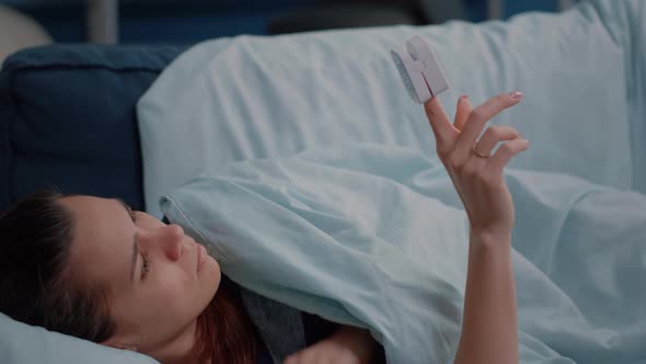 Close Up of Ill Woman Looking at Oximeter on Finger alt