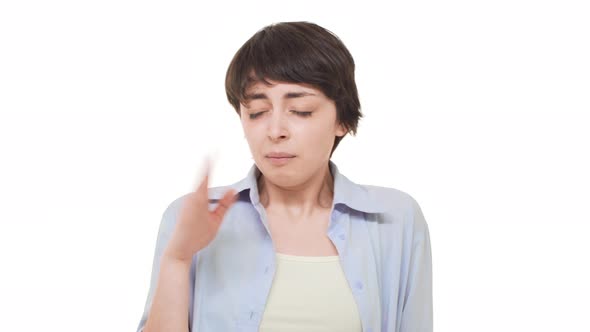 Young Caucasian Female with Short Haircut Wrinkling Her Face From Four Smell Over White Background alt