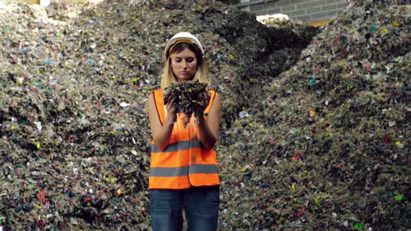 Young Woman in Protective Gear Holds Litter at City Trash Dump alt