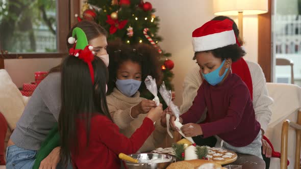 Mothers and children wearing masks making gingerbread cookies and celebrating Christmas