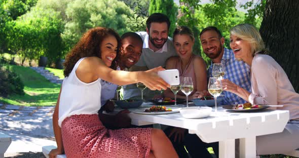 Friends taking a selfie on mobile phone at restaurant alt