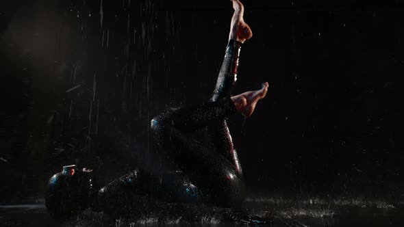 a Woman in a Black Latex Suit Helmet Glasses and Barefoot Lies on Back in the Streams of Water on a alt