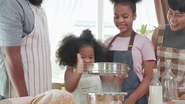 Happy African American family enjoy sifting the bread flour for Family day in holiday