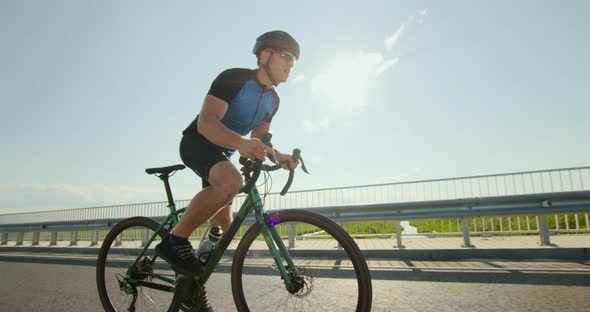 A Sportsman on a Bicycle is Standing on the Pedals and Developing Great Speed alt