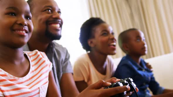 Parents and kids playing video games in living room alt