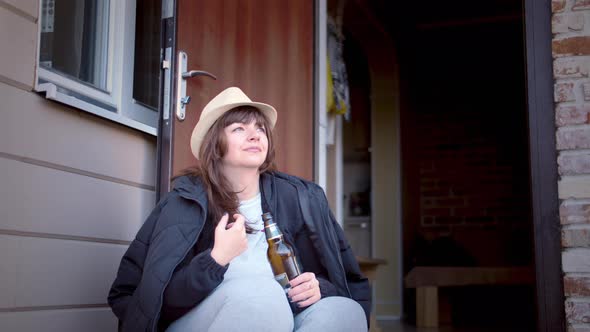 Cowboy Woman Drinking Beer on the Porch of the House Woman Relaxes Near the House and Dreams
