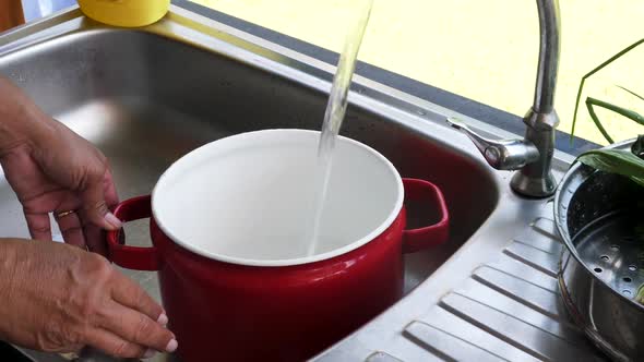 Chef turns on faucet and fills up red cooking pot with water for boiling alt