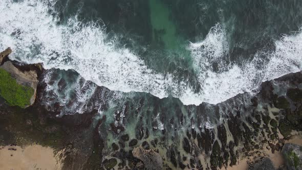 Top down aerial view of giant ocean waves crashing and foaming in coral beach alt