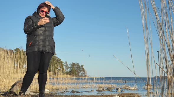 The Lady in Black Coat Taking Selfies on the Seacoast in Finland