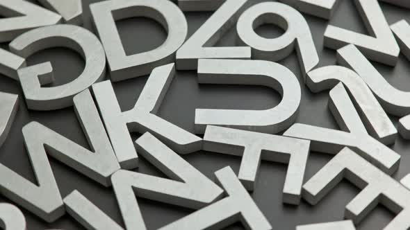 Full Frame Closeup Looped Rotating Background of Silver Metal Letters on Flat Black Surface