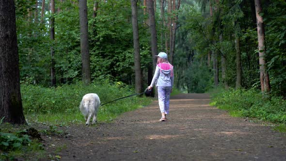 Little Girl Is Walking with a Dog in the Forest