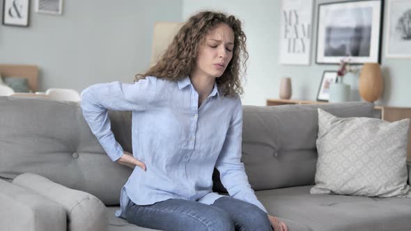 Curly Hair Woman with Spinal Back Pain Sitting on Couch alt