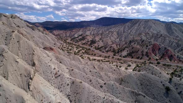 Flying over mountain layers viewing winding road alt