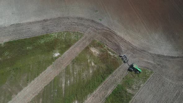 Overhead aerial view of a tractor plowing a field for soybean cultivation alt