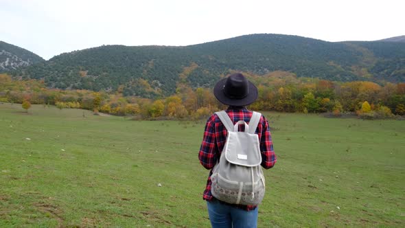 Stylish Hipster Woman with Backpack Walking at Amazing Autumn Field alt