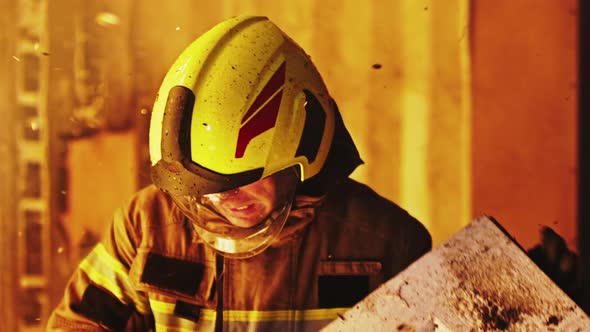 Portrait of Young Firefighter Removing Burned Wood From Burning House alt