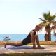 Gymnastics By the Sea  a Blonde Woman Warms Up on Yoga Mat and Stretching Her Legs - VideoHive Item for Sale