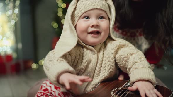 Mom Teaches Baby to Play Guitar at Xmas alt