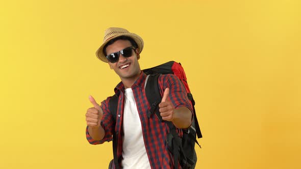 Portrait of handsome Indian tourist man wearing sunglasses saluting and showing thumbs up