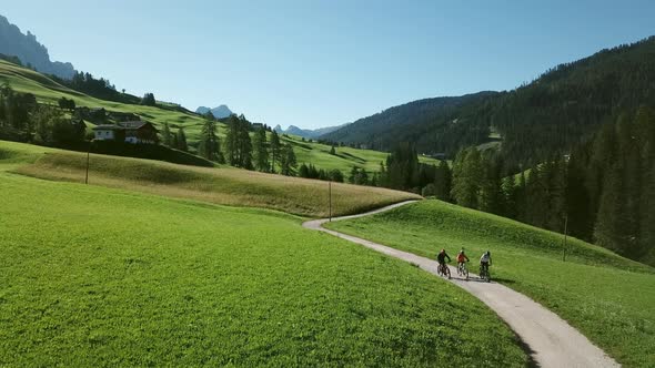 Three people cycling in landscape, Alta Badia, Italy