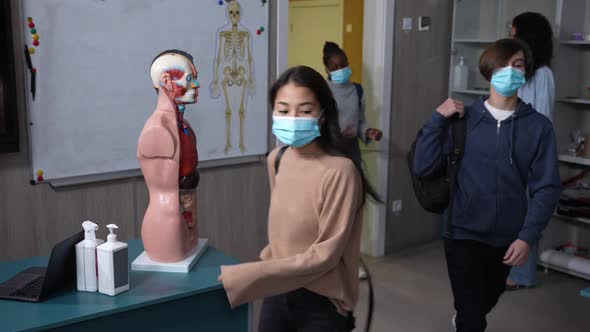 Masked Teen Students Greeting Teacher in Classroom alt
