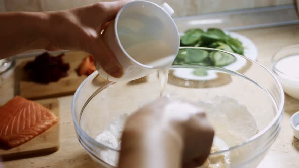 Mixing Fresh Eggs Flour and Milk with Steel Hand Mixer in a Glass Bowl alt