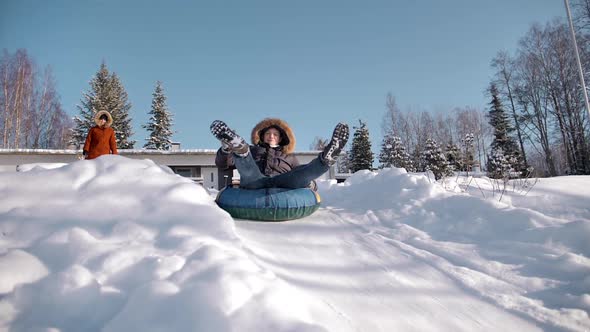 Funny Man is Rolling Down a Hill on an Inflatable Snowtube Showing Peace Gesture alt